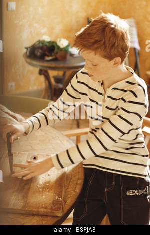 Boy Playing with knife on cutting board Banque D'Images