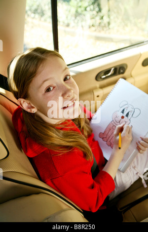 Souriant, heureux jeune fille s'amuse à l'arrière d'une voiture par le dessin et coloriage Banque D'Images