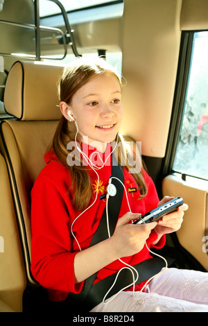 Les jeunes, heureux, smiling girl s'amuse à l'arrière d'une voiture avec un jeu électronique, psp Banque D'Images