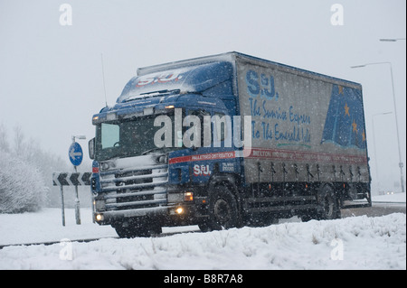 Camion conduisant lentement sur une route enneigée en hiver en Angleterre Banque D'Images