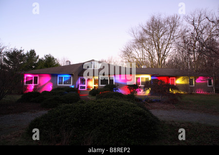 L'avant du ranch maison contemporaine la nuit peints avec différentes couleurs de lumières. Banque D'Images