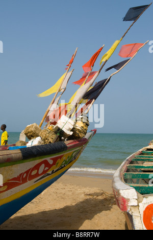 Les bateaux de pêche peints et drapeaux colorés dans le vent sur une plage de Nianing Sénégal Afrique de l'Ouest Banque D'Images