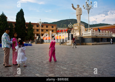 Une famille chinoise admire une statue de Mao au crépuscule à Lijiang, Yunnan Province, China. Banque D'Images