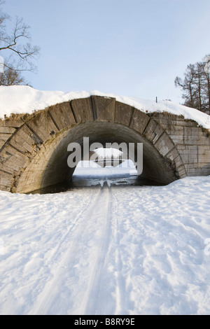 Piste de ski sur la rivière gelée qui passe sous le pont en arc. Banque D'Images