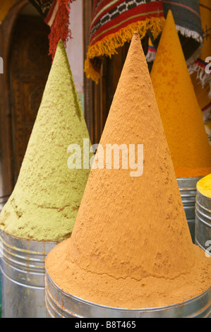 Close up d'épices, orange et jaune formant des pics verts dans des conteneurs métalliques pour la vente au souk à Marrakech Maroc. Banque D'Images