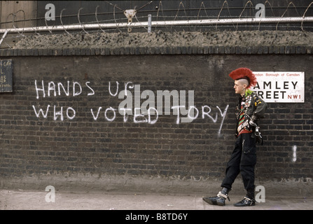 Punk debout devant mur de graffiti disant haut les mains qui ont voté Tory Banque D'Images