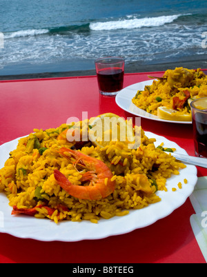 L'Espagnol Paella Valenciana cuit et préparé par la mer, servi avec un vin rouge local. Espagne Banque D'Images