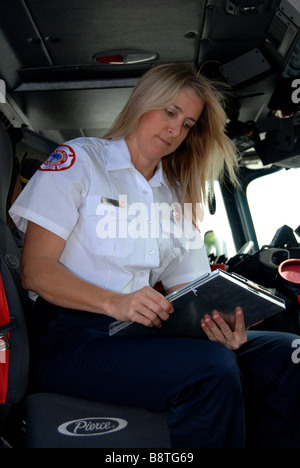 Pompier femelle EMT paramédic en uniforme à la rapport à l'incendie de la cabine moteur Banque D'Images