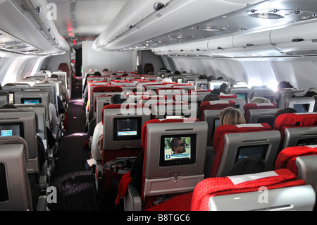 Passagers de l'avion vue sur l'allée et l'arrière sièges intérieur Virgin Atlantic Airbus jet avion cabine passager à bord écran de cinéma de divertissement TV Banque D'Images