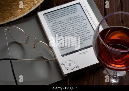 EReader Sony, un appareil de lecture de livres électroniques portables sur terrasse table, avec verre de vin de paille et lunettes de lecture. Banque D'Images