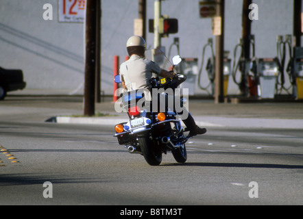 California Highway Patrol Officer sur moto cycle moteur tourne sur chaussée Banque D'Images