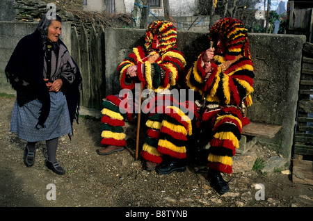 Promenades d'une femme âgée, deux hommes habillés en costumes traditionnels "Caretos" pendant les fêtes de Carnaval dans Podence, Portugal Banque D'Images