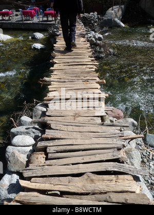 Un homme marche sur une mariée de fortune dans les montagnes de l'Atlas du Maroc. Banque D'Images