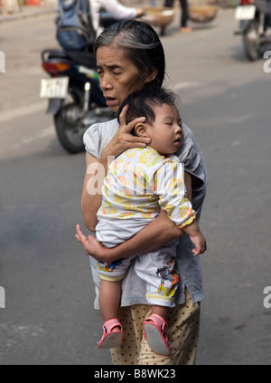 Vietnamienne avec la mendicité des enfants au bord de la route, Saigon, Vietnam Banque D'Images