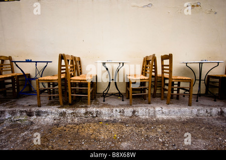 Tables et chaises vides contre le mur à Athènes Banque D'Images