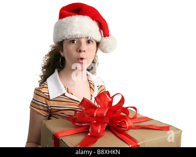 Une jeune fille dans un Santa hat étonné au sujet d'un nouveau cadeau de Noël Banque D'Images