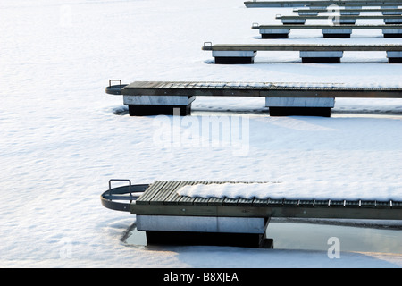 Lignes répétitives de Piers en marina couverte de neige sur le coucher du soleil. Banque D'Images