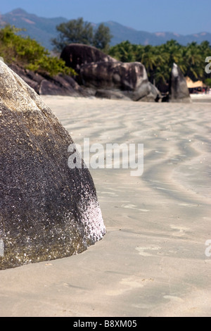 Rocher sur plage de sable fin montrant son patterin à marée basse. Banque D'Images