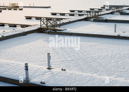 Piers motif dans marina couverte de neige sur le coucher du soleil. Banque D'Images