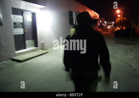 Mystérieux personnage vêtu de noir marcher dans un quartier calme backstreet tard dans la nuit Banque D'Images