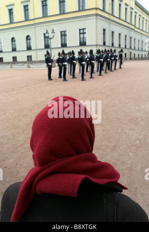 Une femme avec une écharpe rouge regarde la relève de la garde au palais d'Oslo par un beau jour de printemps Banque D'Images