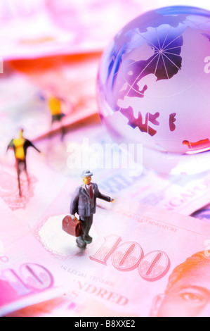 Petit jouet Figurines standing sur l'argent de papier autour d'un globe Banque D'Images