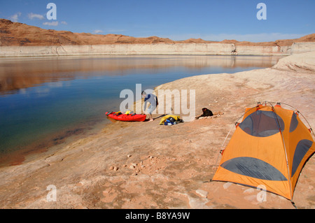 Un kayakiste de mer tire son kayak jusqu'à son camping avec son chien sur le lac Powell, Utah Banque D'Images