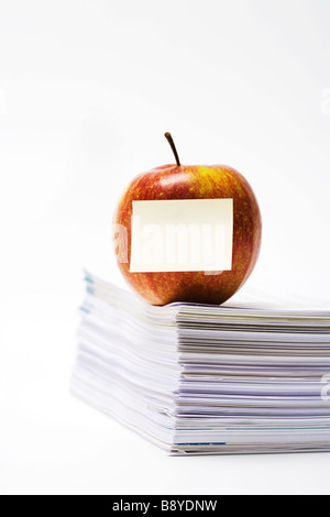 Une pomme sur une pile de papier de près. Banque D'Images