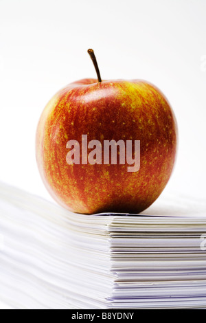 Une pomme sur une pile de papier de près. Banque D'Images