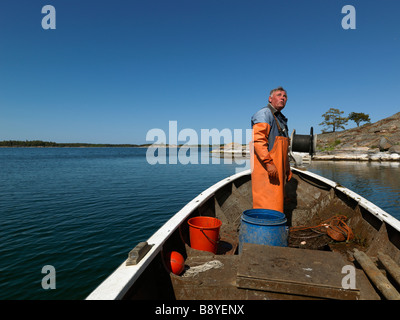 Un homme dans un bateau de pêche en Suède. Banque D'Images