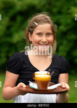 Une jeune fille portant un plateau avec des boissons au chocolat. Banque D'Images