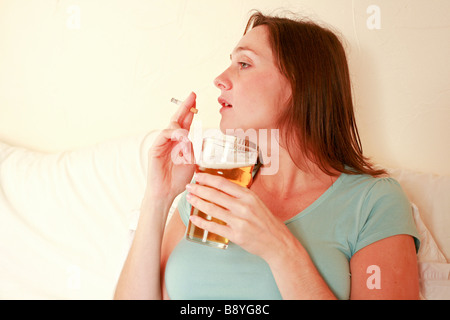 Femme enceinte de boire pinte de bière en verre d'alcool et plus de cigarettes Fumer nuit à foetus baby smiling mauvais régime health Banque D'Images