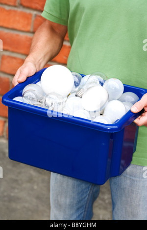 Un homme tenant ampoules pour le recyclage. Banque D'Images