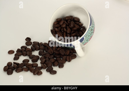 Les grains de café dans la tasse inclinée spilling out Banque D'Images