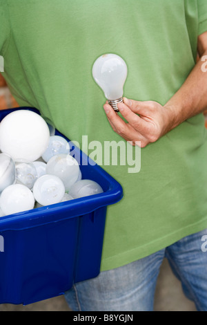 Un homme tenant ampoules pour le recyclage. Banque D'Images