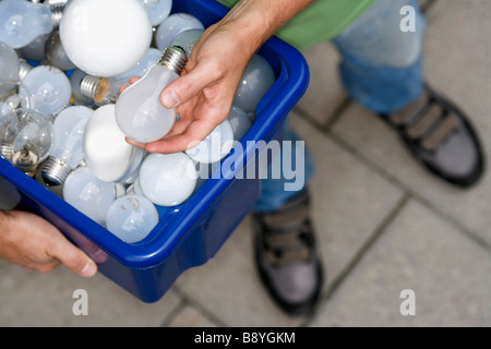 Un homme tenant ampoules pour le recyclage. Banque D'Images