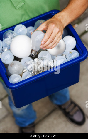 Un homme tenant ampoules pour le recyclage. Banque D'Images