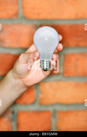 Un homme tenant une ampoule pour le recyclage. Banque D'Images