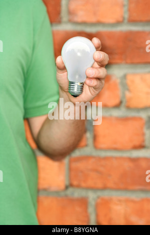 Un homme tenant une ampoule pour le recyclage. Banque D'Images