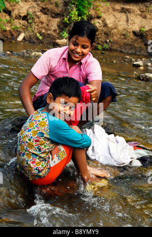 Les soeurs et frères à laver les vêtements dans la rivière près du camp de réfugiés de Maela,Tak,le nord de la Thaïlande. Banque D'Images