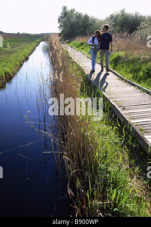 Wicken Fen Cambridgeshire un couple en train de marcher le long de la promenade à côté du cours d'eau