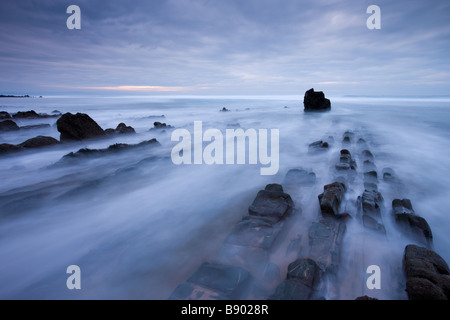 Au cours de la ruée vers les vagues barres rocheuses à Sandymouth Bay en Cornouailles du nord de l'Angleterre Banque D'Images