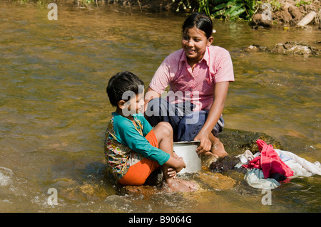 Les soeurs et frères à laver les vêtements dans la rivière du camp de réfugiés de nearMaela,Tak,le nord de la Thaïlande. Banque D'Images