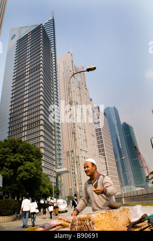 Un homme musulman ouïghour vend des sucreries traditionnelles de la province de Xinjiang en face du quartier financier de Pudong, Shanghai. Banque D'Images