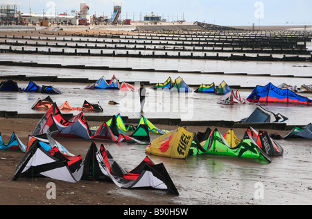 Un jeune homme marche au milieu des kites surf sur le sable à Hunstanton. Banque D'Images