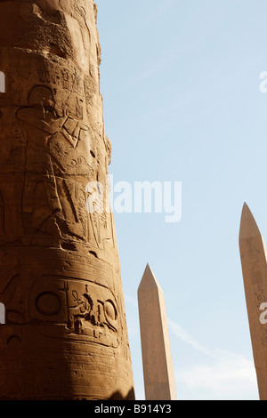 Colonne en pierre gravée de hiéroglyphes, obélisques jumeaux d'Hatshepsout et Thoutmosis I derrière, salle hypostyle, Karnak, Louxor, Egypte Banque D'Images