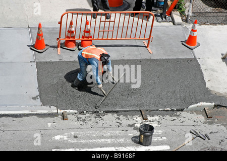 Le lissage de l'homme un trottoir de béton humide fraîchement coulé.