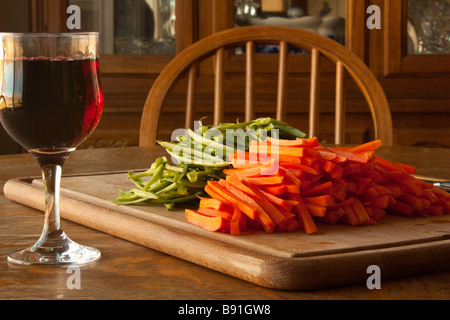 Une planche à découper, jullienned les carottes et les haricots verts avec un couteau et un verre de vin pour le chef Banque D'Images