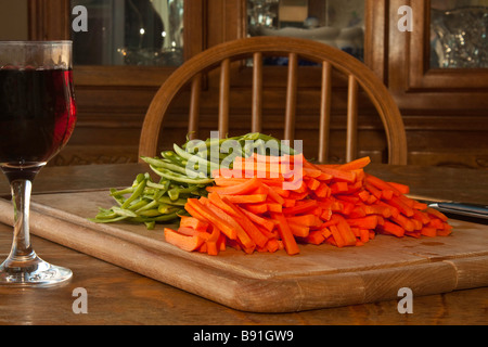 Une planche à découper, jullienned les carottes et les haricots verts avec un couteau et un verre de vin pour le chef Banque D'Images
