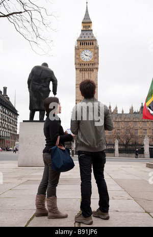 Oriental asiatique couple de touristes dans 20s / 30s visiter Londres, Big Ben et des chambres du Parlement et la statue de Winston Churchill Banque D'Images